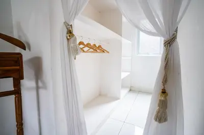 a white room with a curtain and a window at Villa Polly in Seminyak