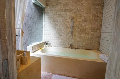 a bath tub in a bathroom with a window at Villa Polly in Seminyak