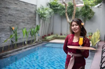 a woman holding a tray with a drink on it at Cozy Umalas Guesthouse in Kerobokan