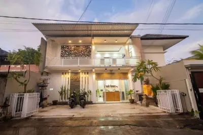 a large white house with a balcony on top of it at Cozy Umalas Guesthouse in Kerobokan