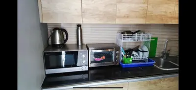 a kitchen counter with a microwave and a sink at Cozy Umalas Guesthouse in Kerobokan