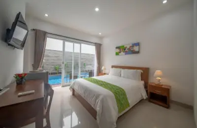 a bedroom with a bed and a desk and a window at Cozy Umalas Guesthouse in Kerobokan