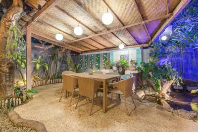 a dining room with a table and some plants at Villa Maloa in Denpasar