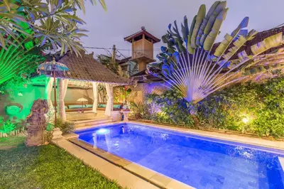 a swimming pool in front of a house with a garden at Villa Maloa in Denpasar