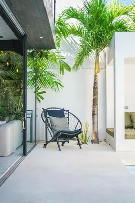 a chair on a porch with a palm tree at Villa Bali Townhouse 3 - Modern 2BR Villa with pool - PERFECT LOCATION in Canggu