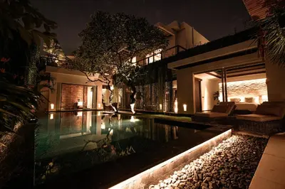 a house with a swimming pool at night at Sunset Palms Beach Villa in Jimbaran