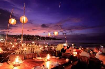 a group of people sitting at tables with lights at Sunset Palms Beach Villa in Jimbaran