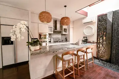 a kitchen with a large counter with bar stools at Sunset Palms Beach Villa in Jimbaran