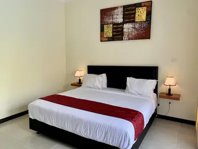 a bedroom with a large white bed with two lamps at Davit Guesthouse Nusa Dua in Nusa Dua
