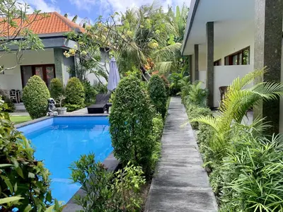 a garden with a swimming pool and a house at Davit Guesthouse Nusa Dua in Nusa Dua