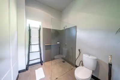 a bathroom with a toilet and a glass shower at Villa Wiraja 1 - Modern 4 bdr villa in Berawa in Canggu