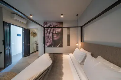 a bedroom with a large bed and a painting on the wall at Villa Wiraja 1 - Modern 4 bdr villa in Berawa in Canggu