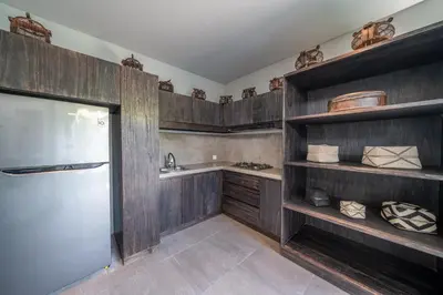 a kitchen with wooden cabinets and a stainless steel refrigerator at Villa Wiraja 2 - Classy 4 bdr villa in the heart for Canggu in Canggu