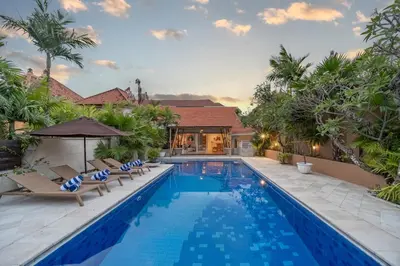 a swimming pool with lounge chairs and a villa at Villa Margaretta in Seminyak