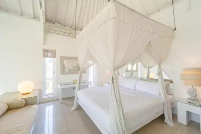 a bedroom with a canopy bed and a couch at Villa Margaretta in Seminyak