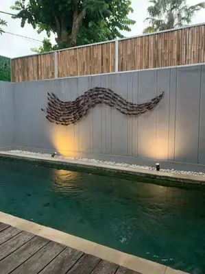 a swimming pool with a wooden fence next to a wall at Modern Balinese Villa with Scenic View in Nusa Dua