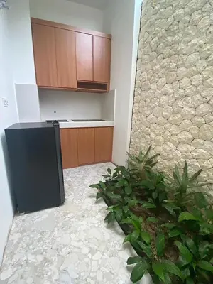 a kitchen with a black refrigerator and a stone wall at Puspa Ayu Villas & Apartments in Kuta