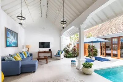 a living room with a blue couch and a pool at Villa Sintra - 2 BR luxury in tranquil location, walk to beach in Seminyak
