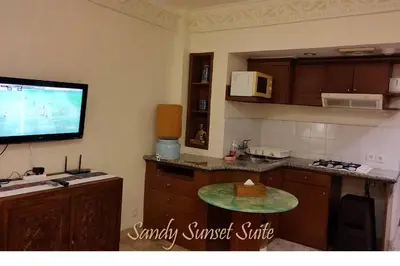 a kitchen with a tv on the wall and a table at Jayakarta Residence - Sandy Sunset Suite 1BR - 6432 in Seminyak
