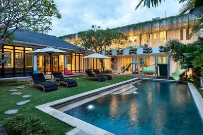 a resort with a swimming pool with chairs and a slide at Villa Iluka by SooBali in Seminyak