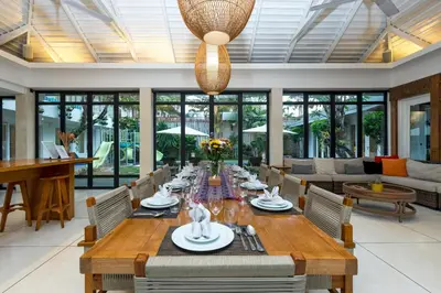 a dining room with a long table and a couch at Villa Iluka by SooBali in Seminyak