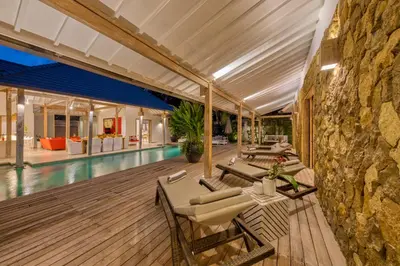an indoor pool with tables and chairs and a stone wall at PROMO 4 bd Spacious villa in strategic location in Seminyak