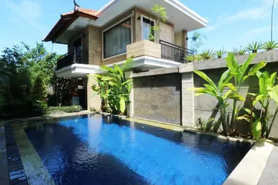 a swimming pool in front of a house at Kondra Premiere Guest House Kuta in Kuta