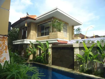 a house with a swimming pool in front of it at Kondra Premiere Guest House Kuta in Kuta
