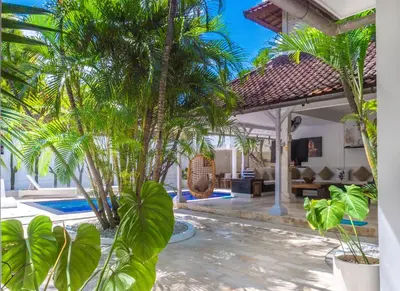 a villa with a swimming pool and palm trees at Ocean Star 1 in Seminyak