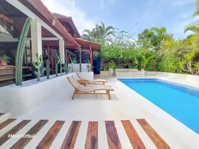 a swimming pool with a chair next to a house at Ocean Star Villa Four Bedrooms Seminyak in Seminyak