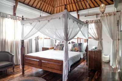 a bedroom with a canopy bed and a chair at Ocean Star Villa Four Bedrooms Seminyak in Seminyak