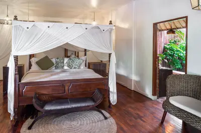 a bedroom with a canopy bed and a chair at Ocean Star Villa Four Bedrooms Seminyak in Seminyak