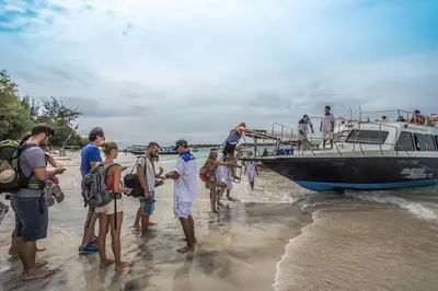 a group of people getting on a boat on the beach at PIMA Homestay in Pesanggaran