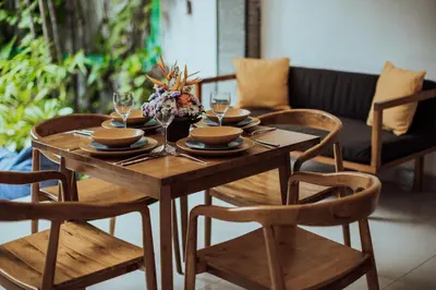 a wooden table with plates and glasses and chairs at Padma Villa I in Legian