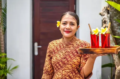 a woman holding a plate of food with flowers on it at Villa Joyosa in Seminyak