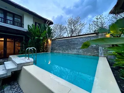 a swimming pool in front of a house at Mai Villa in Jimbaran