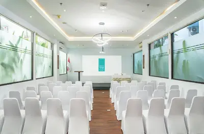an empty lecture room with white chairs and a podium at Cross Vibe Paasha Atelier Bali Kuta in Kuta