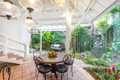 a patio with a table and chairs and a garden at La Villa Oberoi (6 BR) in Seminyak