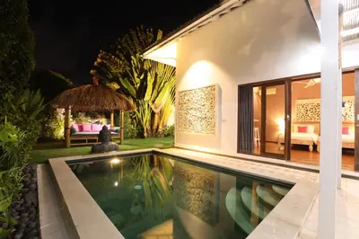 a villa with a swimming pool at night at La Villa Oberoi (2 BR) in Seminyak