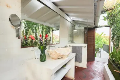 a bathroom with a vase of flowers on a counter at La Villa Oberoi (2 BR) in Seminyak