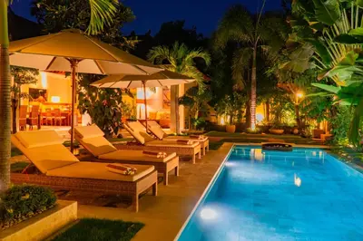 a swimming pool with lounge chairs and an umbrella at Villa Dayak in Seminyak