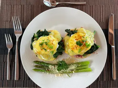 a white plate of food with eggs and asparagus at Villa Dayak in Seminyak