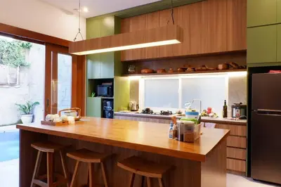 a kitchen with a large wooden counter top with stools at Villa Bale Damai Denpasar in Seminyak