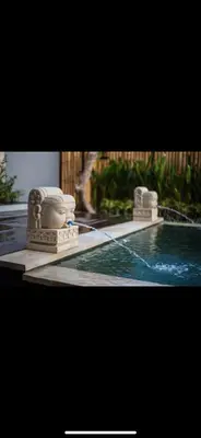 a swimming pool with a fountain in the middle at Legian Bisma Suite in Seminyak