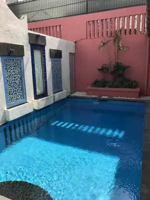 a swimming pool in front of a pink building at 5 Bedroom Holiday Villa - Kuta Regency B8 in Kuta