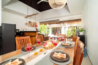 a dining room with a table with food and wine glasses at Villa bella wilson in Seminyak