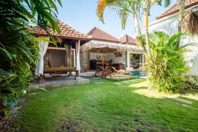 a backyard of a house with a bench and palm trees at Villa bella wilson in Seminyak