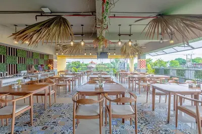 a restaurant with wooden tables and chairs and windows at Horison Le Aman Bali in Jimbaran