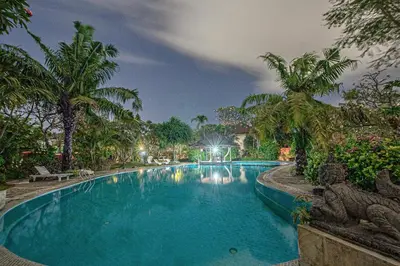 a swimming pool in a resort with palm trees at Panorama Cottages I in Legian