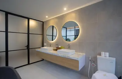 a bathroom with two sinks and two mirrors at The Kon's Villa Bali Seminyak in Seminyak